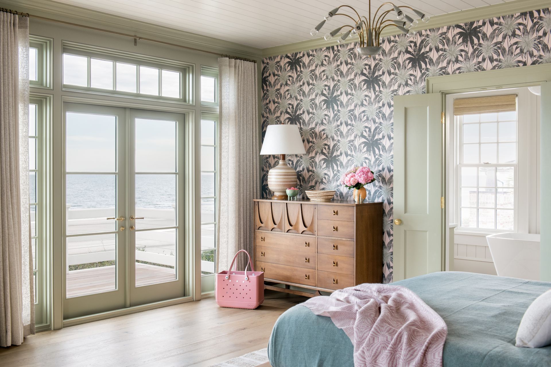 Bedroom styling with lighting and made bed looking towards doors