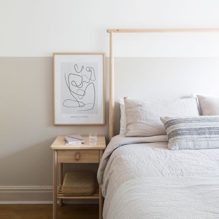 Neutral bedroom with linen sheets on bed beside wooden table