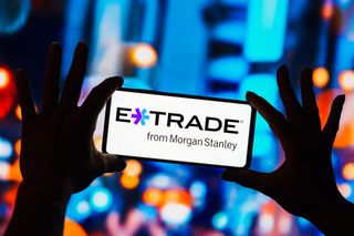 E*Trade logo on smartphone with city buildings lit up in background