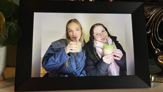 Aeezo 10.1-inch digital picture frame showing two girls sipping mocktails with an inset border