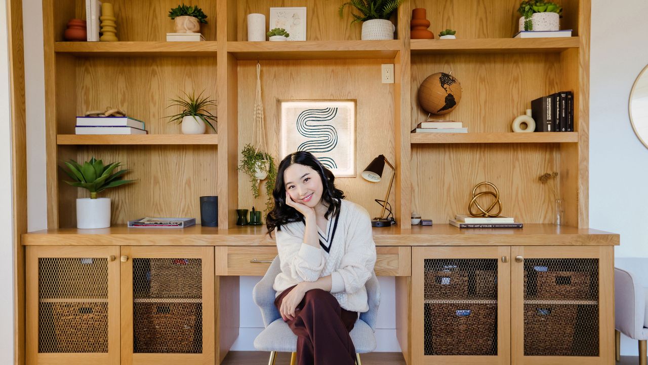 Jenn Im sitting in front of wooden built-in shelving styled with pieces from Lowe&#039;s