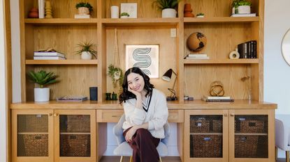 Jenn Im sitting in front of wooden built-in shelving styled with pieces from Lowe's