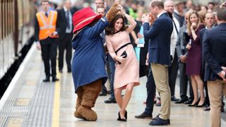 Kate Middleton dancing with a Paddington Bear mascot