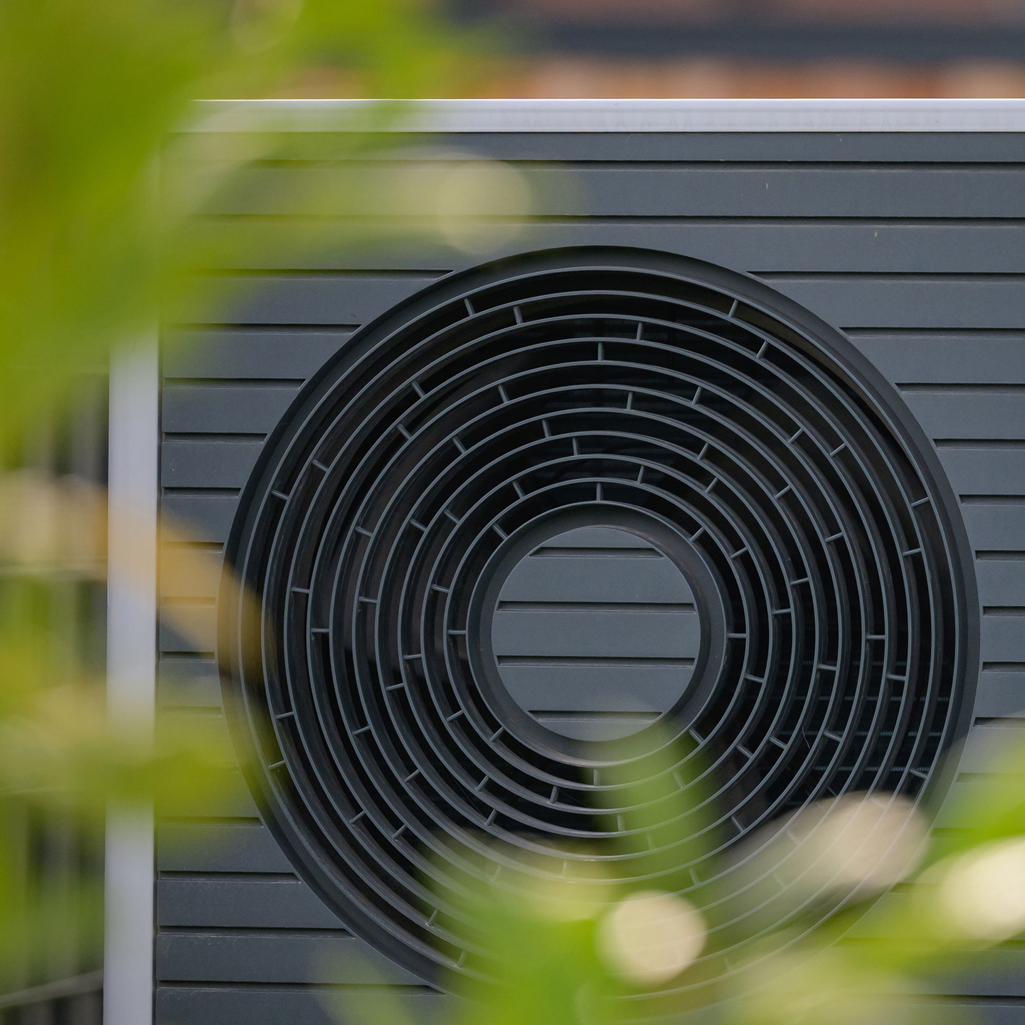 Heat pump with blurred foliage in foreground