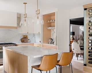 modern dining kitchen with white cabinets, marble island and tan brown stools