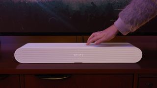 Sonos Ray in living room, with person touching the controls