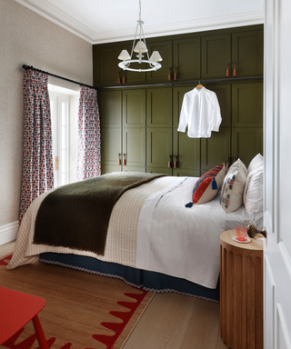 compact bedroom with bed and green painted cabinetry and rug and bedside table