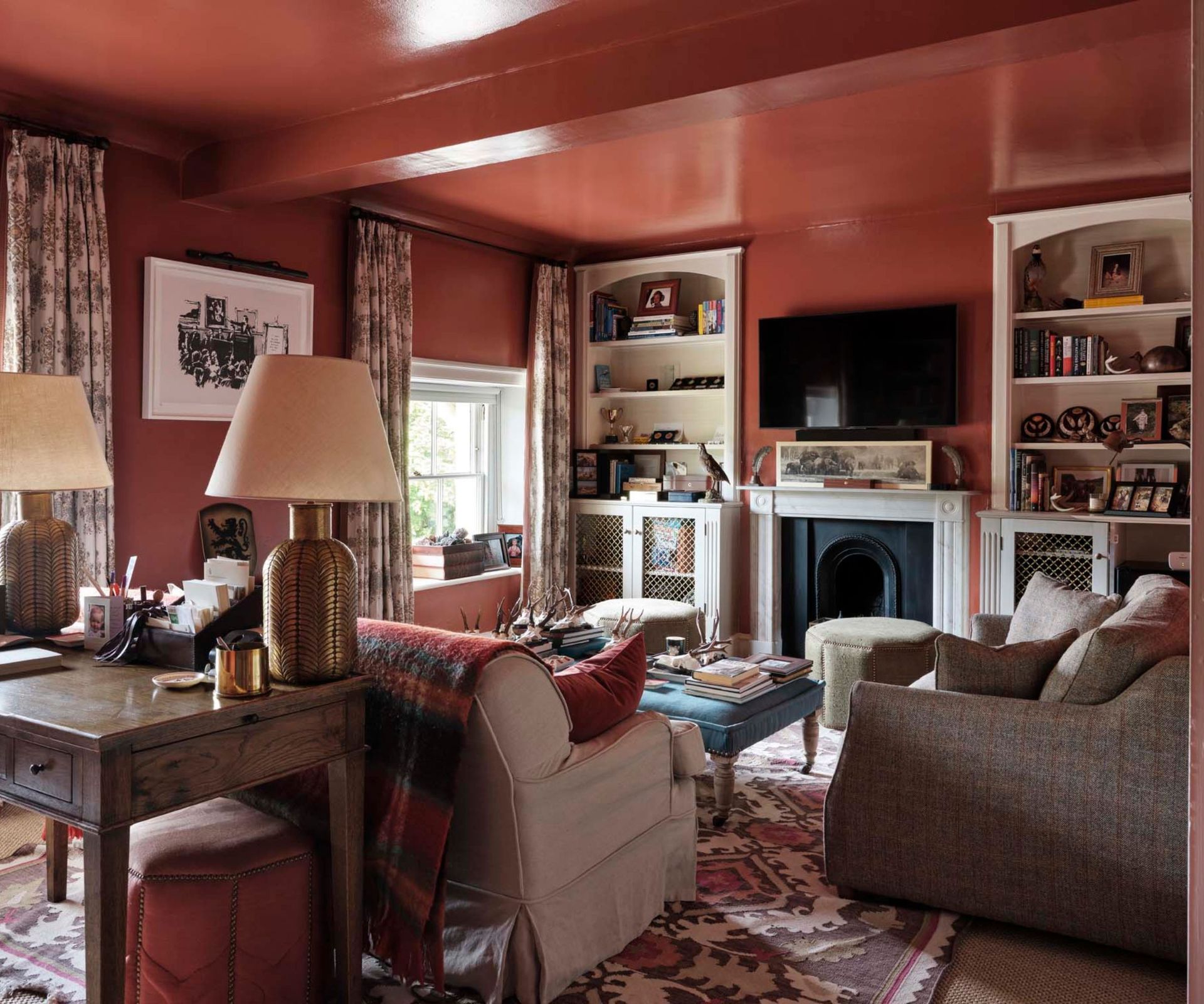 color drenched gloss red living room with a fireplace, alcove book shelves, two sofas, and a large traditional rug