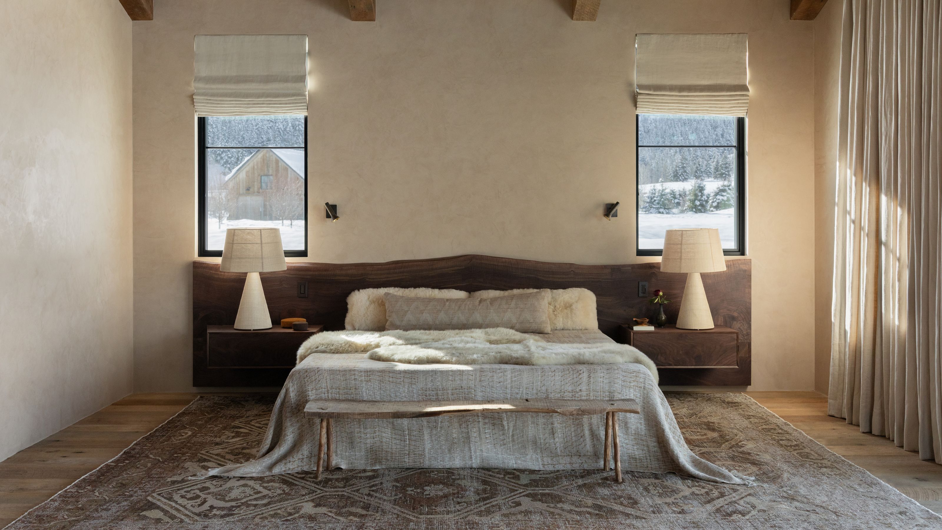 a large primary bedroom with a vaulted ceiling, a neutral linen dressed bed with a walnut headboard