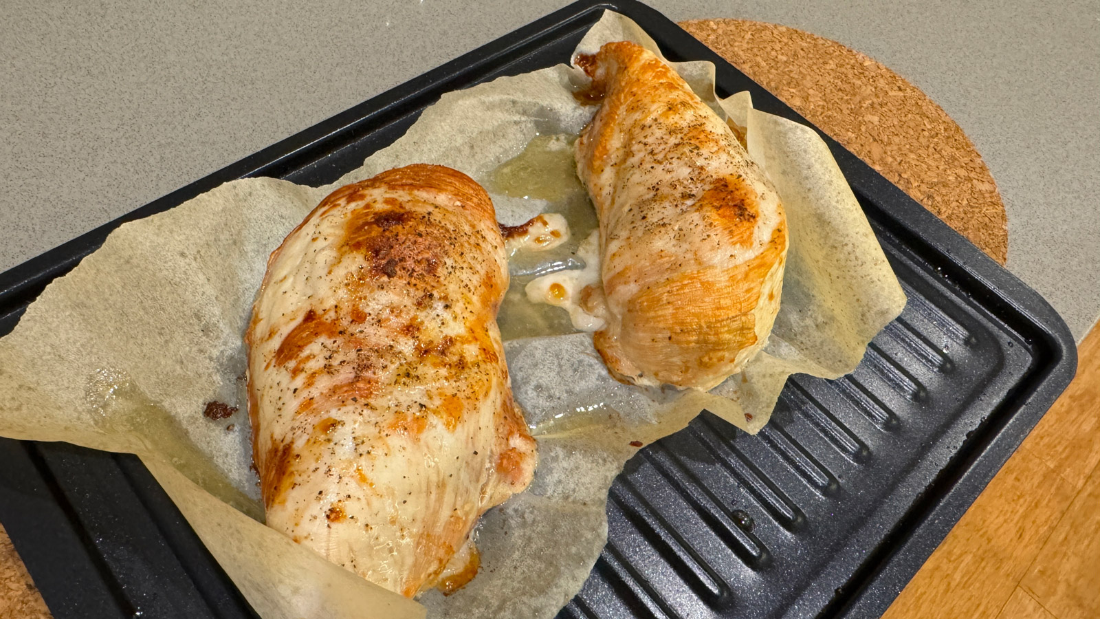 Two cooked chicken breasts on a small roasting tray