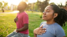 Young couple practicing yoga in a summer park.