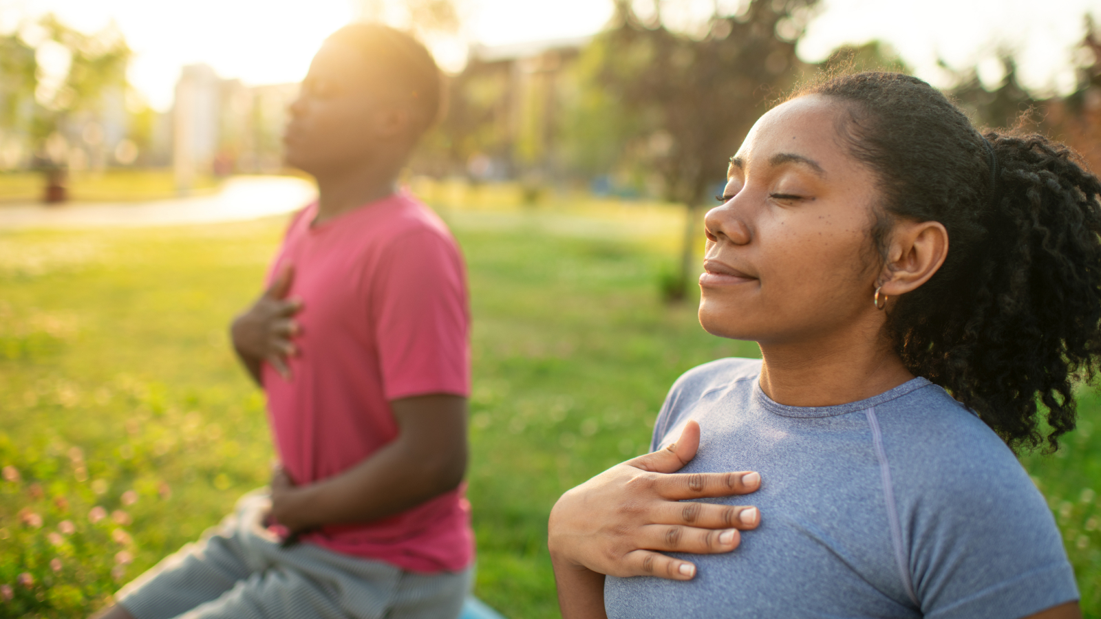 Young couple practicing yoga in a summer park.
