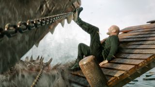 A shark wrapped in chains tries to bite Jason Statham in The Meg 2: The Trench.