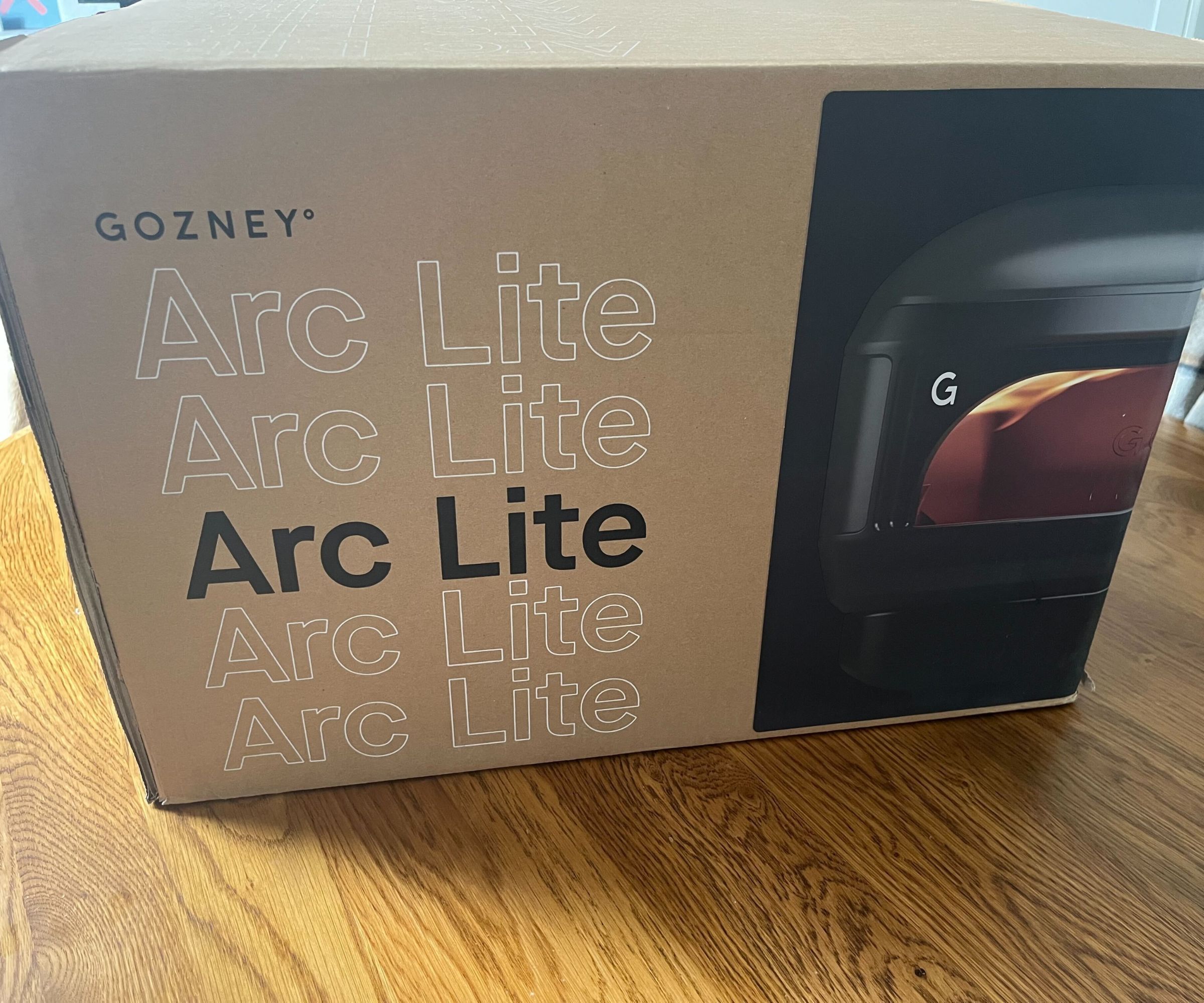 The brown cardboard box with the Gozney Arc Lite on the front. 