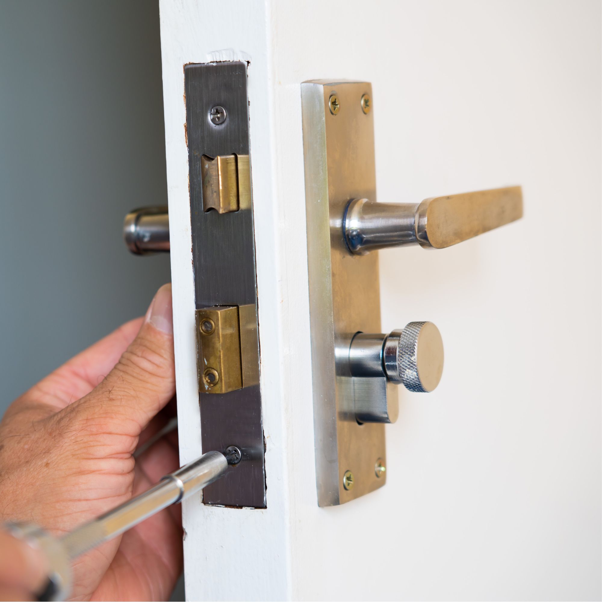 Removing an old door handle from a door with a screwdriver