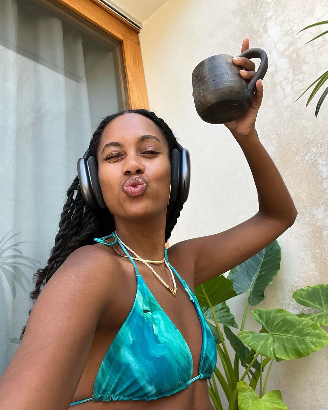 Claire Most wears an aquamarine bikini top and long twists while on a tropical getaway