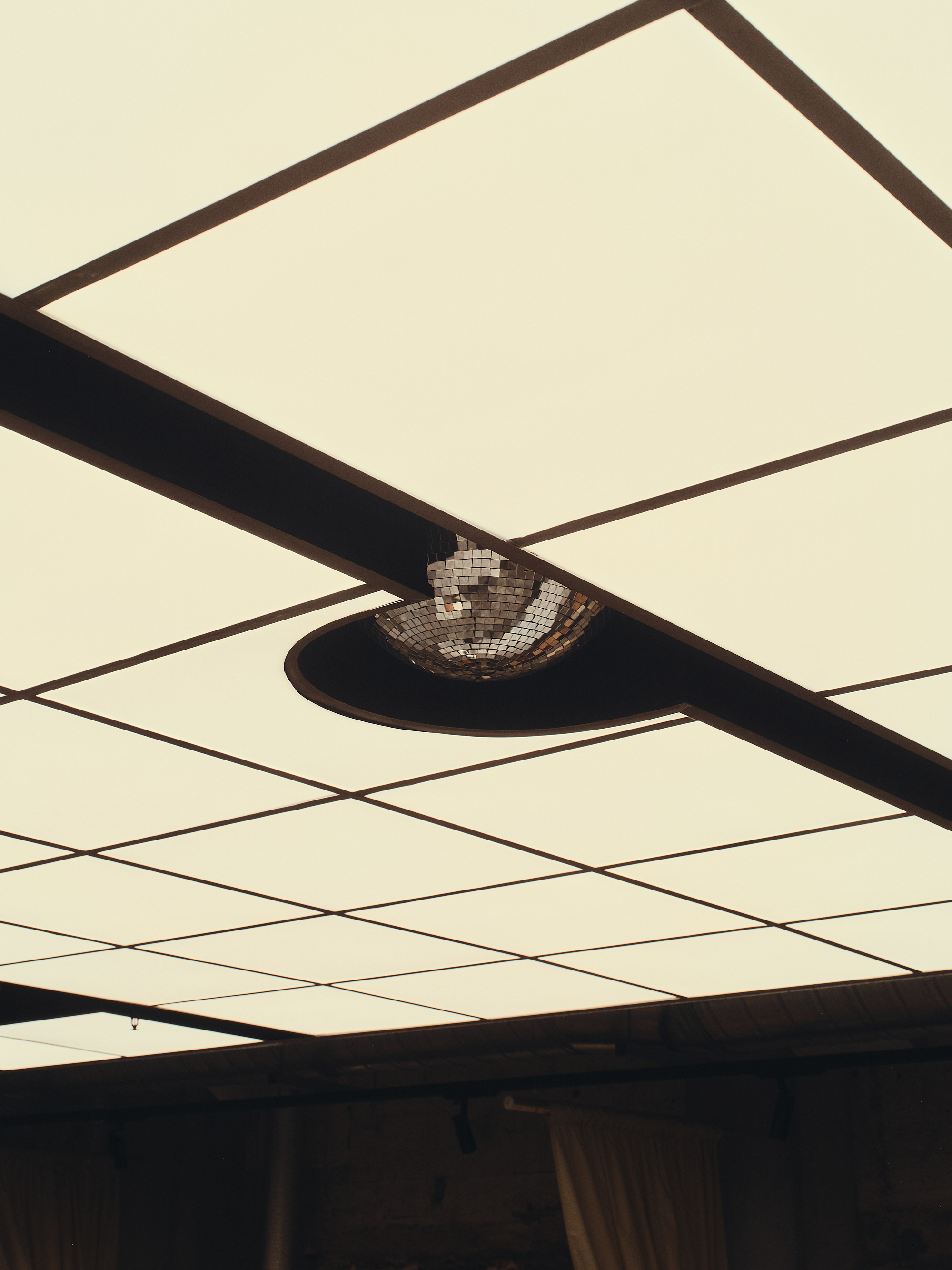 a ceiling with square light tiles that opens up to expose a disco ball