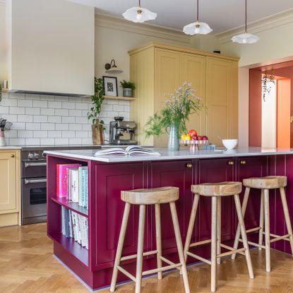 kitchen with purple island and yellow cabinetry and wooden bar stools Bee Holmes