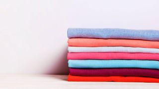 Simple image of brightly coloured folded tshirts on a white background