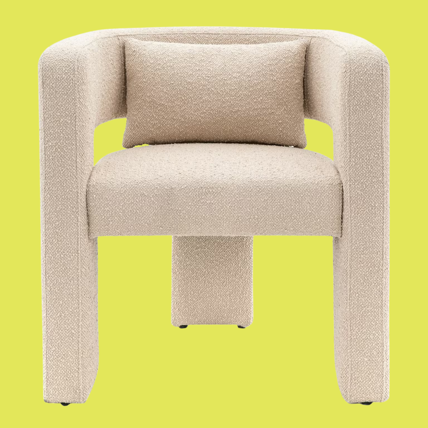 An off-white three-legged armchair with a bolster pillow