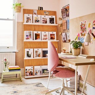 home office with pink office chair, open shelving display unit, desk and plywood walls