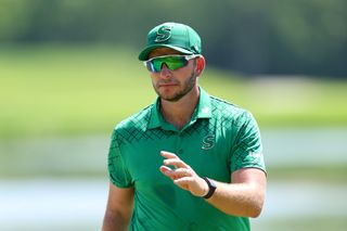 Dean Burmester waves to the crowd after holing a putt