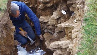 A man excavates inside a rocky pit