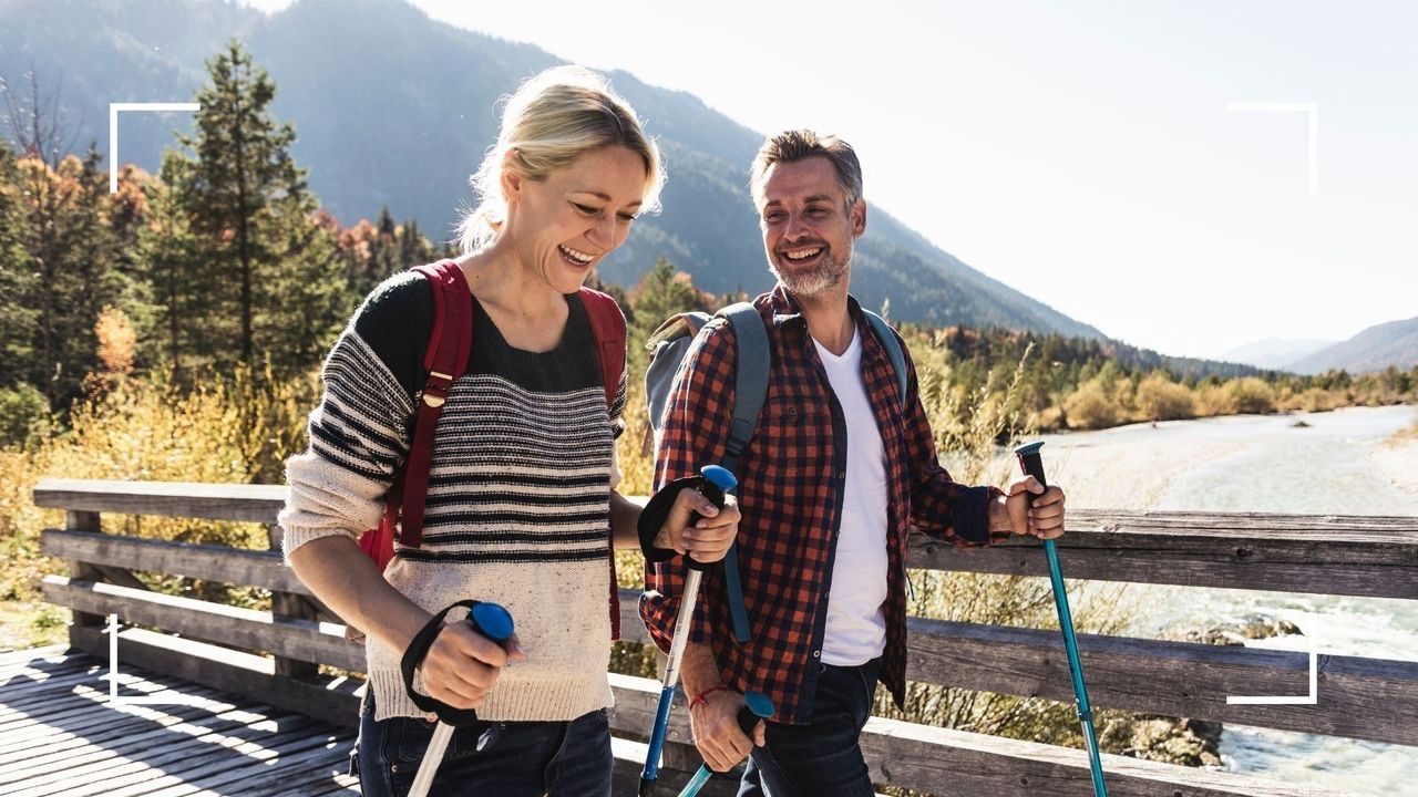 Couple walking with a backpack and walking poles, rucking outdoors