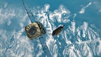 a cube shaped satellite moves toward a spacecraft hovering above some snowy mountains on earth.