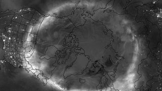 grey scale image over the northern hemisphere, showing a white wispy circle of aurora.