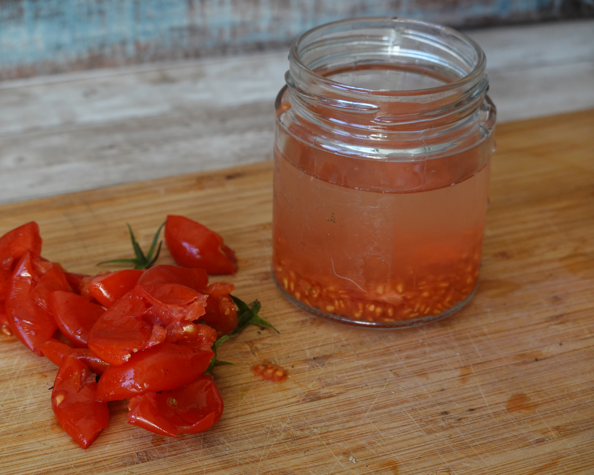 Fermenting tomato seeds in a glass jar with water, preparing them for drying and saving for future gardening and harvesting