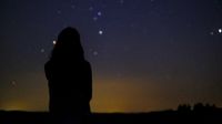 a woman looks at a sky full of stars
