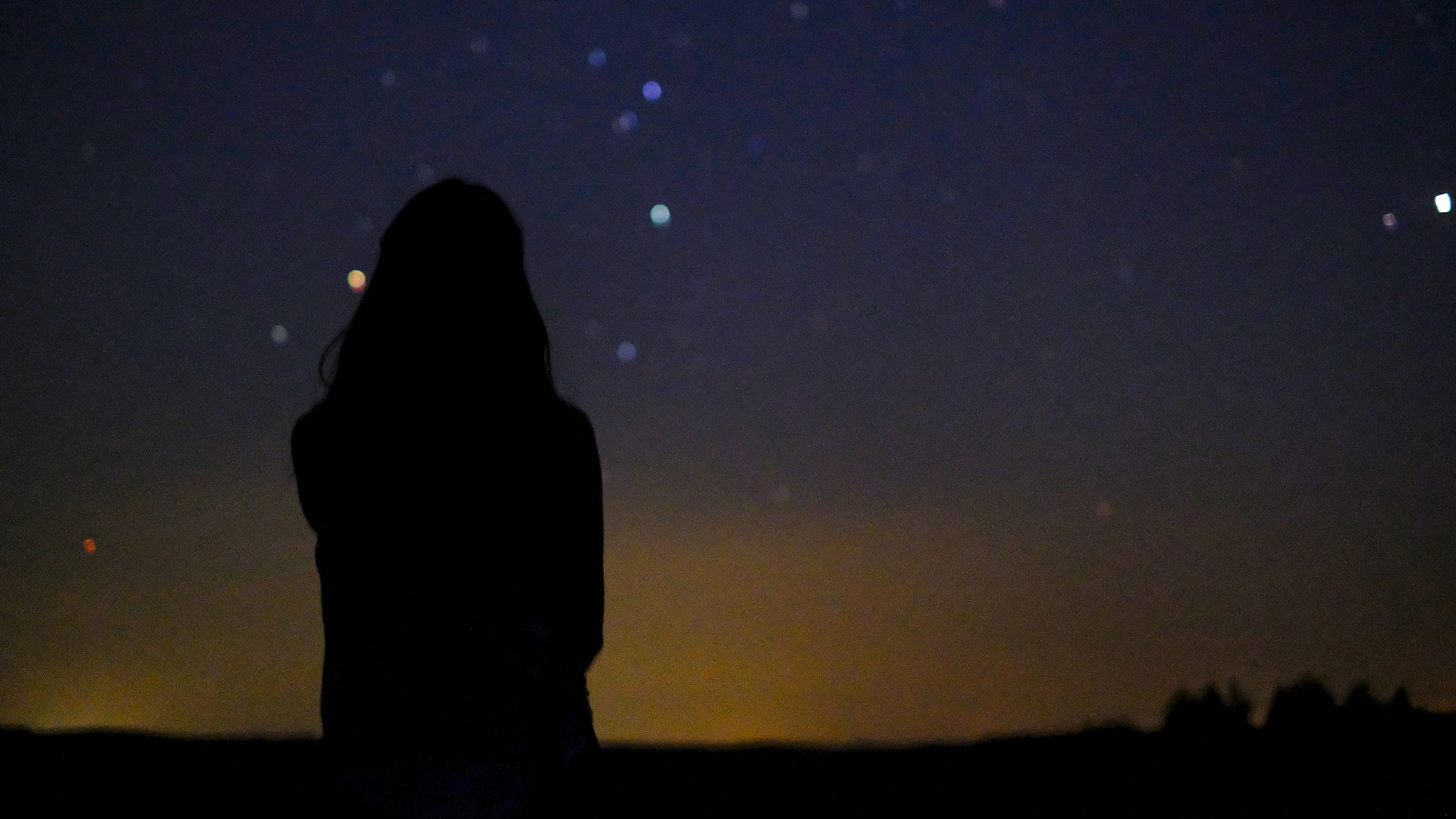 a woman looks at a sky full of stars
