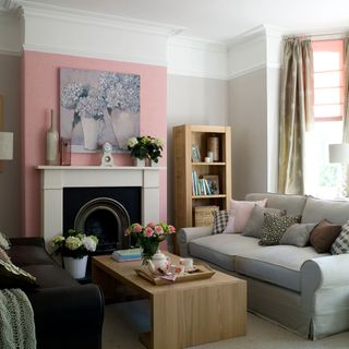 A pink painted chimney breast in a light living room with grey sofas