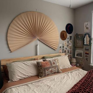 Boho bedroom space with neutral-colored fan above the bed and dusty rose bedding