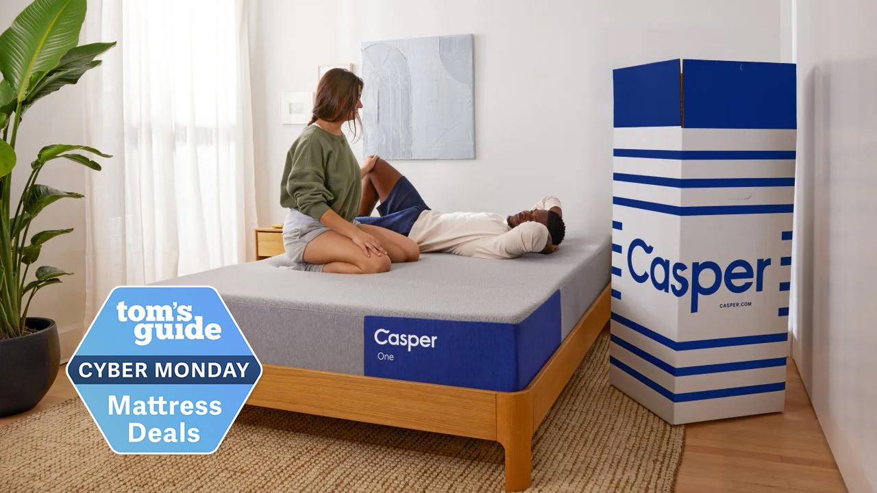 Casper The One memory foam mattress in a box placed on a wooden bed frame, and with a Tom&#039;s Guide blue Cyber Monday deals badge overlaid on the bottom left hand corner