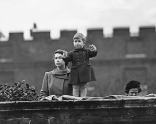 Princess Elizabeth (later Queen Elizabeth II), left, and Prince Charles watching a procession, during the visit of Queen Juliana of the Netherlands, from the wall of Clarence House, London, 22nd November 1950