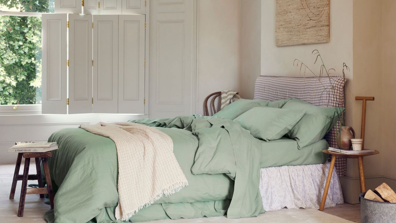 Sage Green Bedding on a bed against cream walls and an open window. 