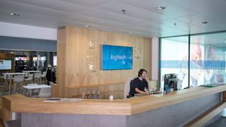 En receptionist sidder og taler i telefon foran et stort Logitech logo