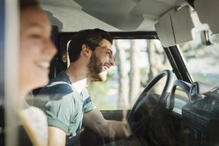 A side view of a happy couple in a car on a roadtrip.