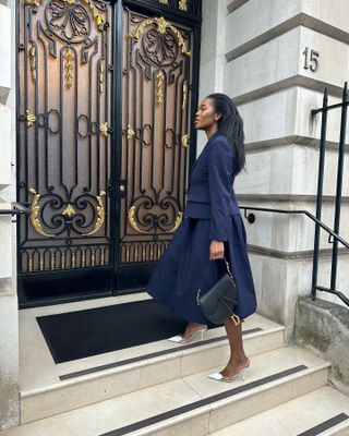 @nlmarilyn wears a navy skirt with a matching tailored blazer and white shoes