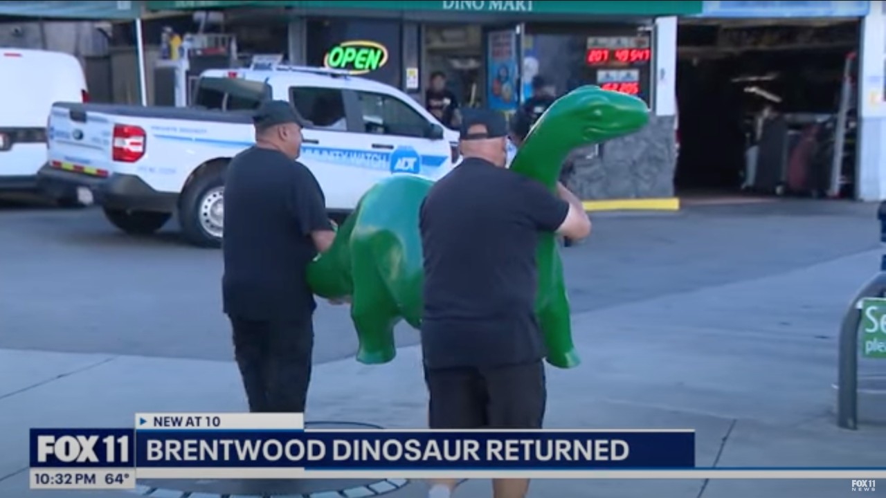 Two Brentwood Sinclair gas station employees carrying the returned dinosaur, Claire.