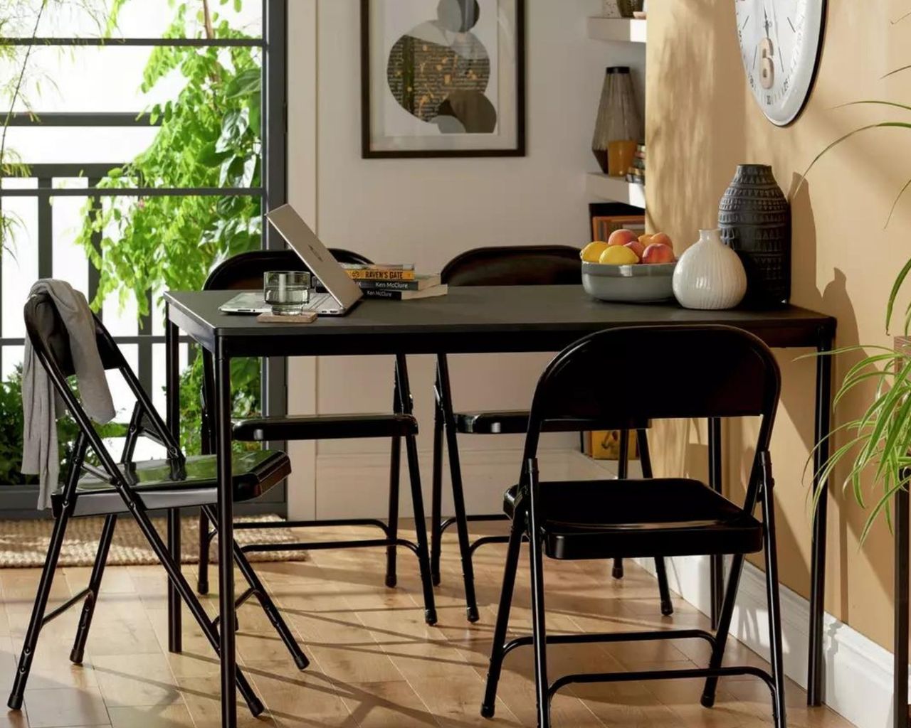 Habitat Stella Metal 6 Seater Dining Table with black foldable chairs pushed against a beige wall