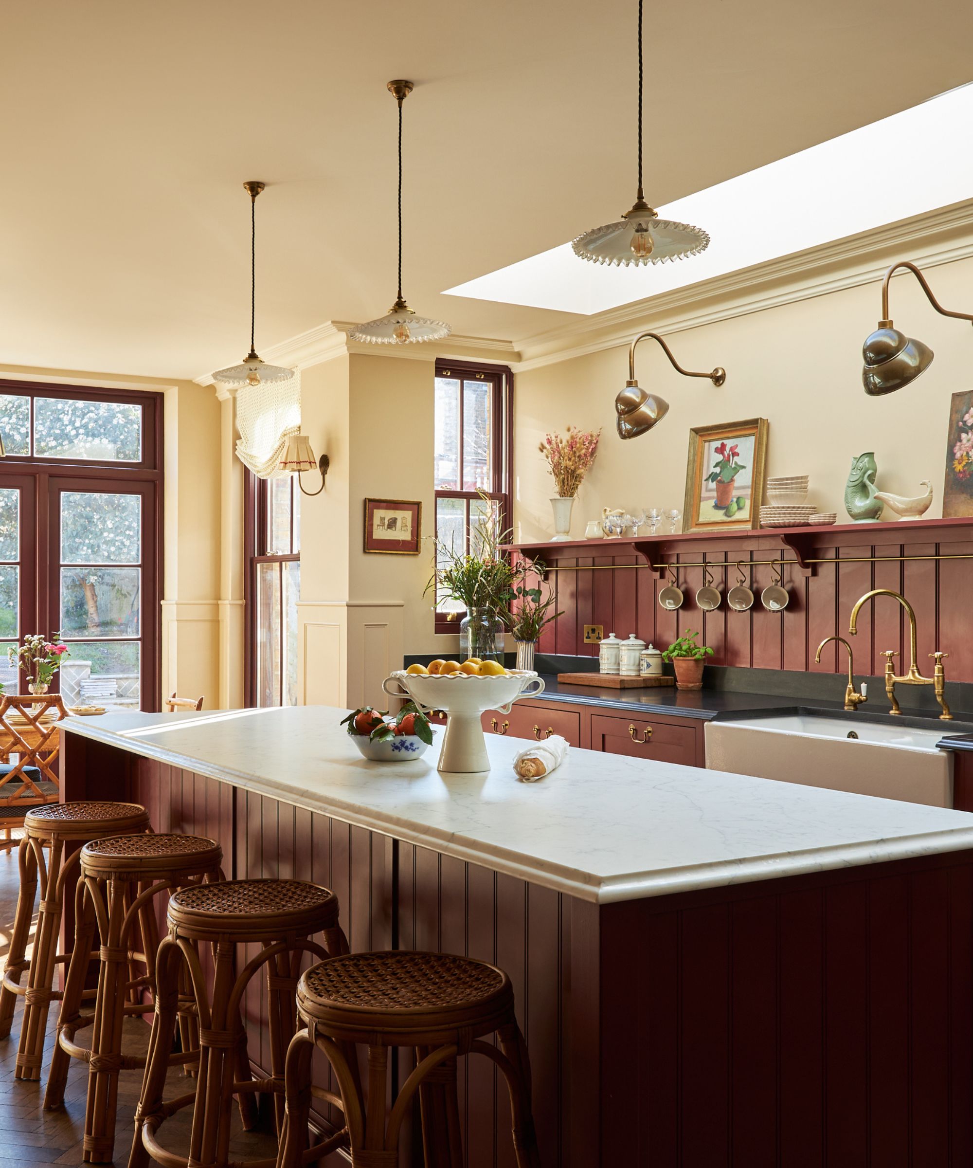 a large kitchen with oxblood red cabinets and paneled backsplash, black countertops, and warm neutral walls