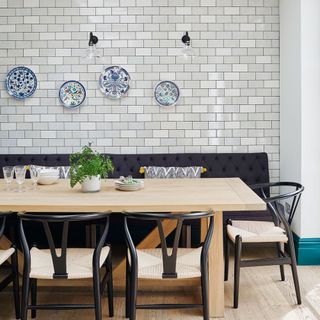 A dining table in a dining room with metro tile wall and plates as decor