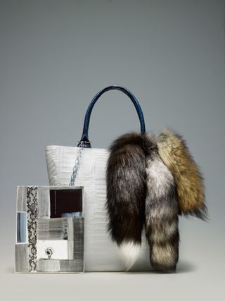 White bag with black handle, three fur tails, and an accessory attached with a chain