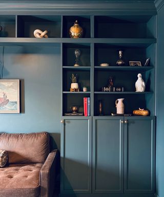 A home office with built-in shelving wrapped around a brown leather sofa made with IKEA BILLY bookcases