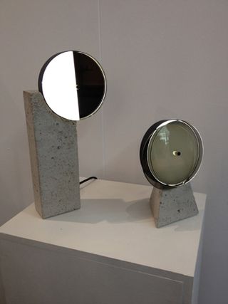 White wall, white block viewing platform, two concrete base lamps with metal and mirror design