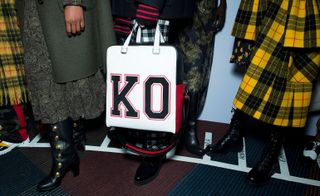A close-up of 'K.O' college-style bag, paired with paisley and tartan skirts