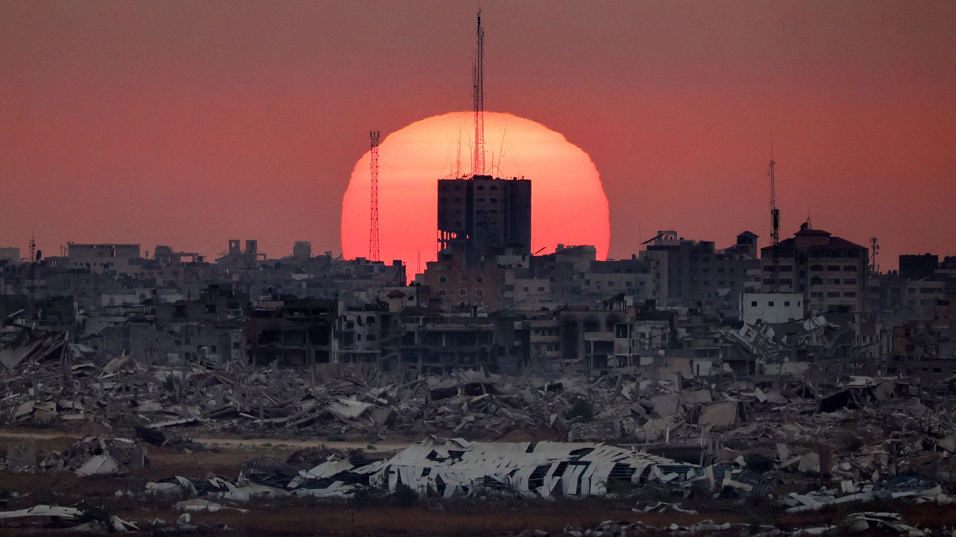 
                                The sun sets behind destroyed buildings on the Gaza Strip in Palestine
                            